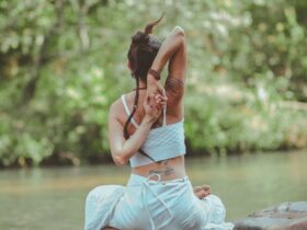 Mujer practicando yoga al aire libre junto al agua en la naturaleza