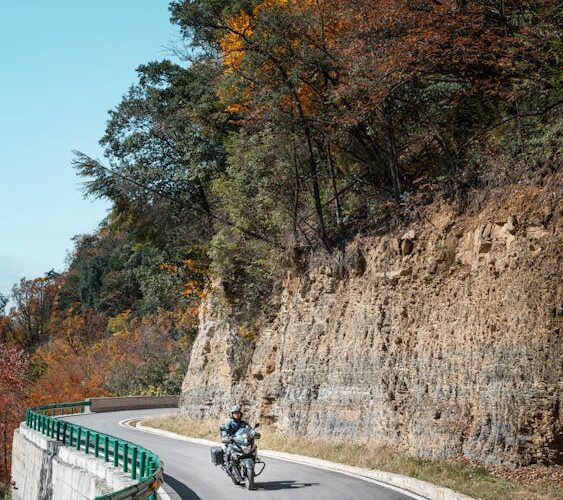 Motociclista recorriendo una espectacular carretera de montaña en otoño