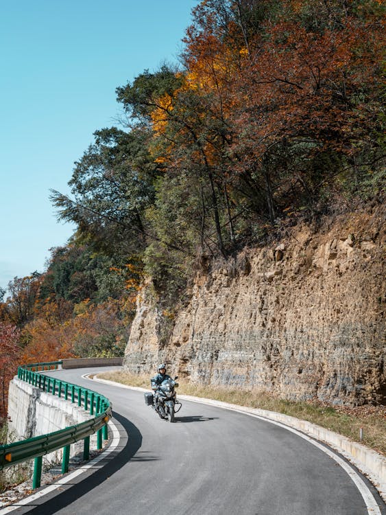 Motociclista recorriendo una espectacular carretera de montaña en otoño